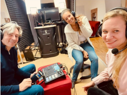 Drei Personen mit Headsets sitzen um ein Mischpult in einem Tonstudio.